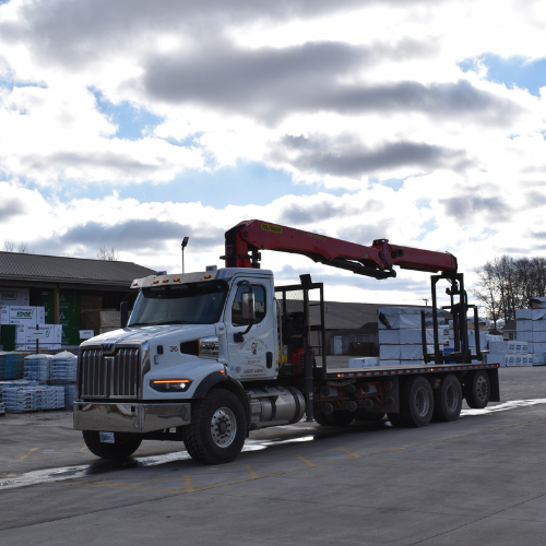 A box trucks with empty long beds and a crane.